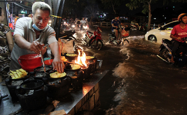 Le Van Chin makes Vietnamese pancakes while surrounded by floodwater on Tran Xuan Soan Street in District 7, Ho Chi Minh City December 5, 2017. Photo: Tuoi Tre