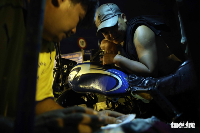 A repairman fixes a motorbike that has broken down. Photo: Tuoi Tre