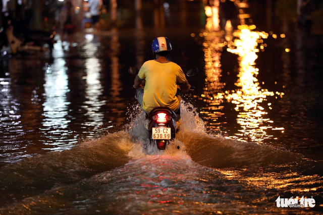A motorcyclist struggles through waist-deep floodwater. Photo: Tuoi Tre