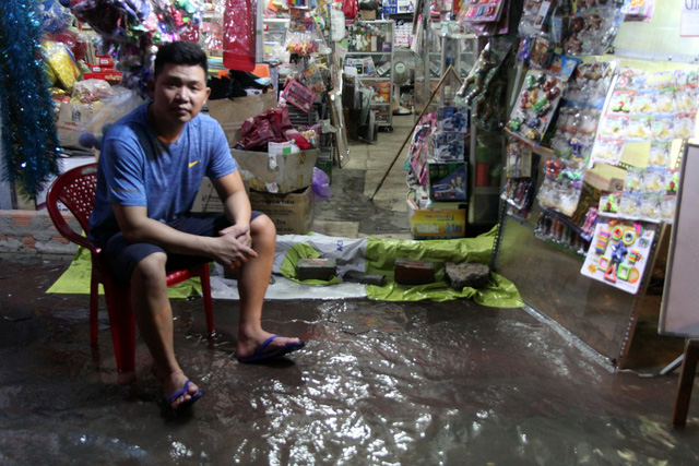 Thanh, a shop owner on Tran Xuan Soan Street in District 7, Ho Chi Minh City, waits for water to recede on December 5, 2017. Photo: Tuoi Tre