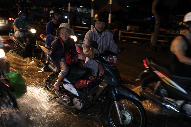 A man pushes his motorbike through floodwater. Photo: Tuoi Tre