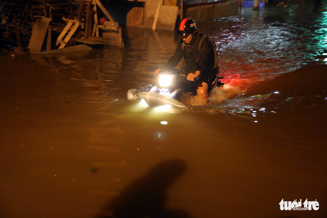 A motorcyclist struggles through waist-deep floodwater. Photo: Tuoi Tre