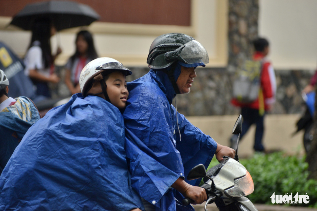 A father takes his son home in the rain in Ho Chi Minh City on December 25, 2017. Photo: Tuoi Tre