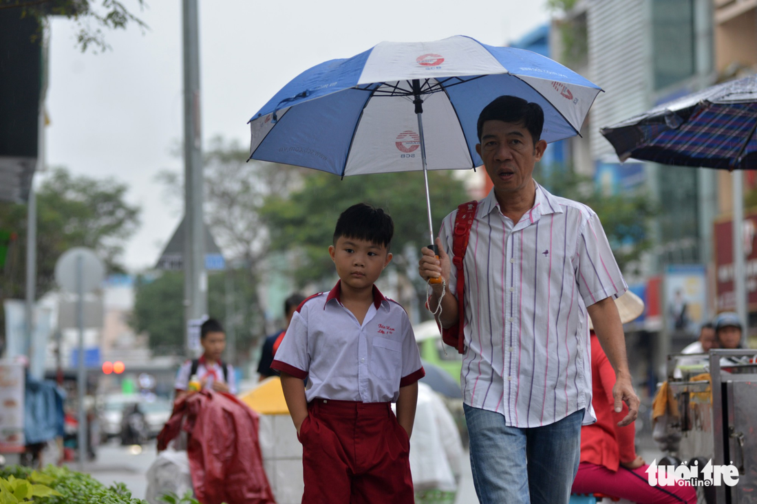 A man walks his son to school in the rain in Ho Chi Minh City on December 25, 2017. Photo: Tuoi Tre