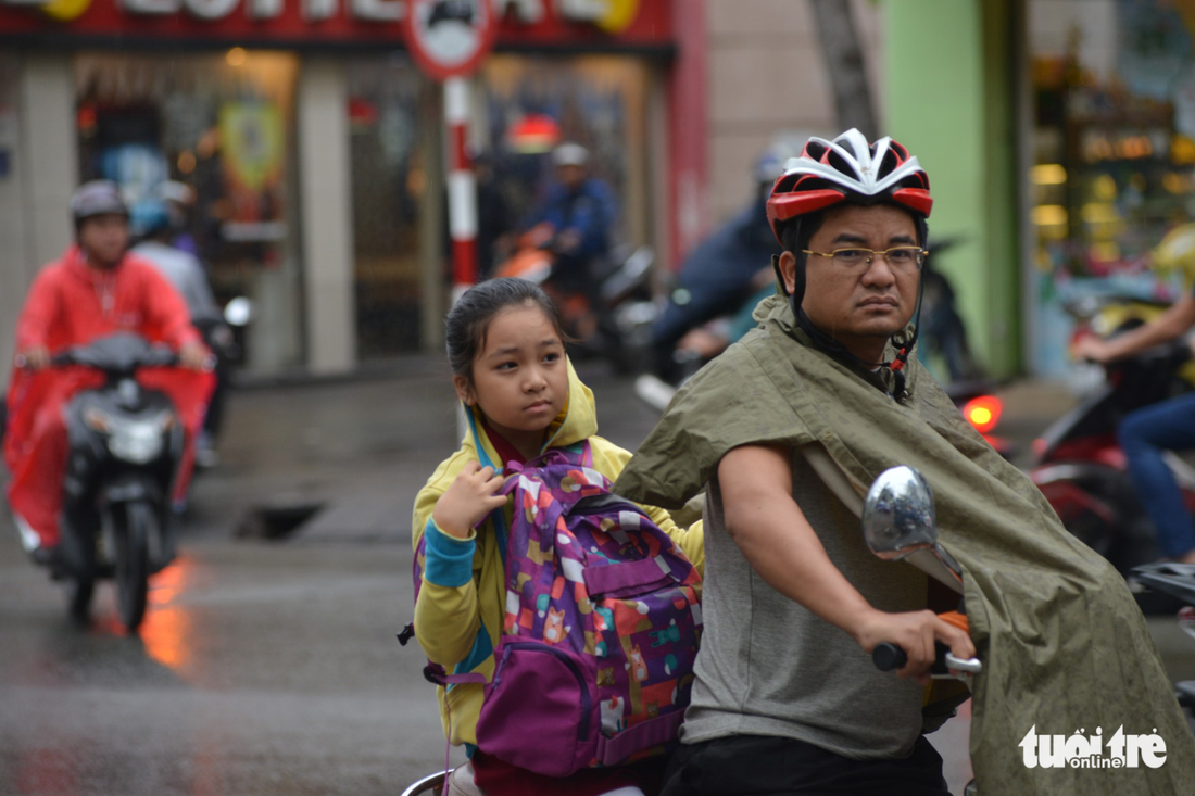 A father takes his daughter home in the rain in Ho Chi Minh City on December 25, 2017. Photo: Tuoi Tre