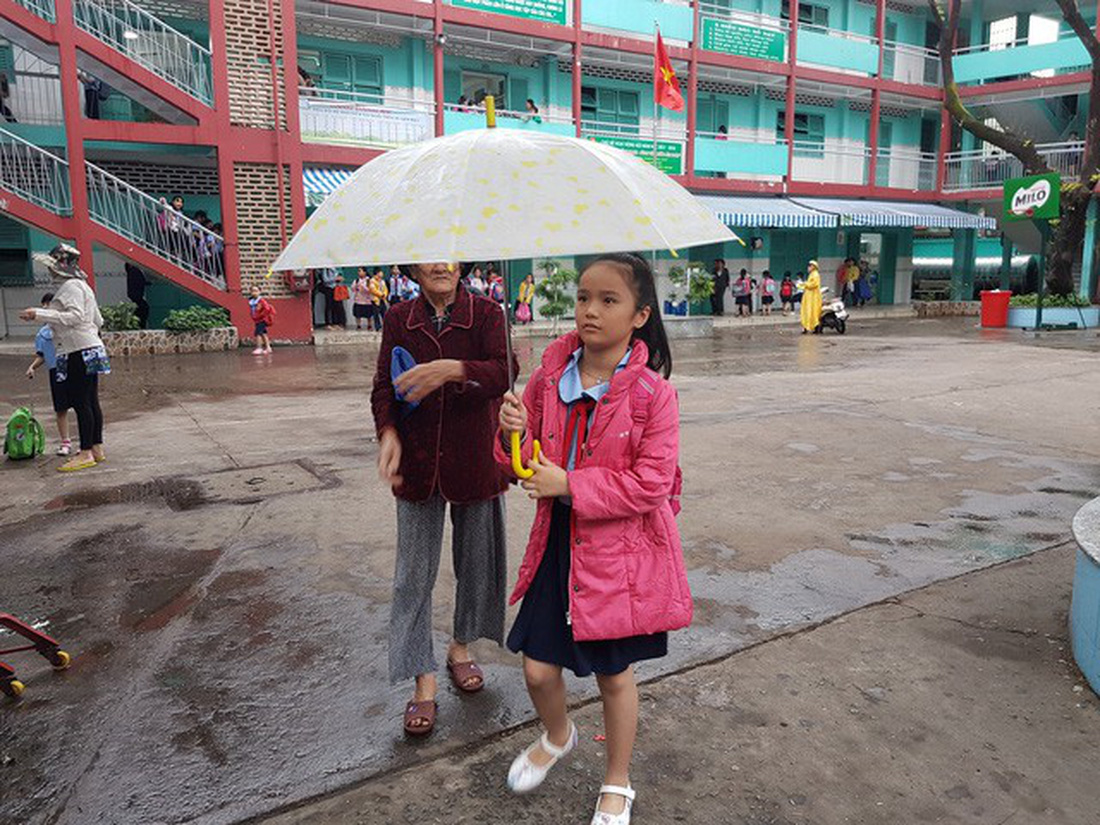 A mother takes her daughter home in the rain in Ho Chi Minh City on December 25, 2017. Photo: Tuoi Tre