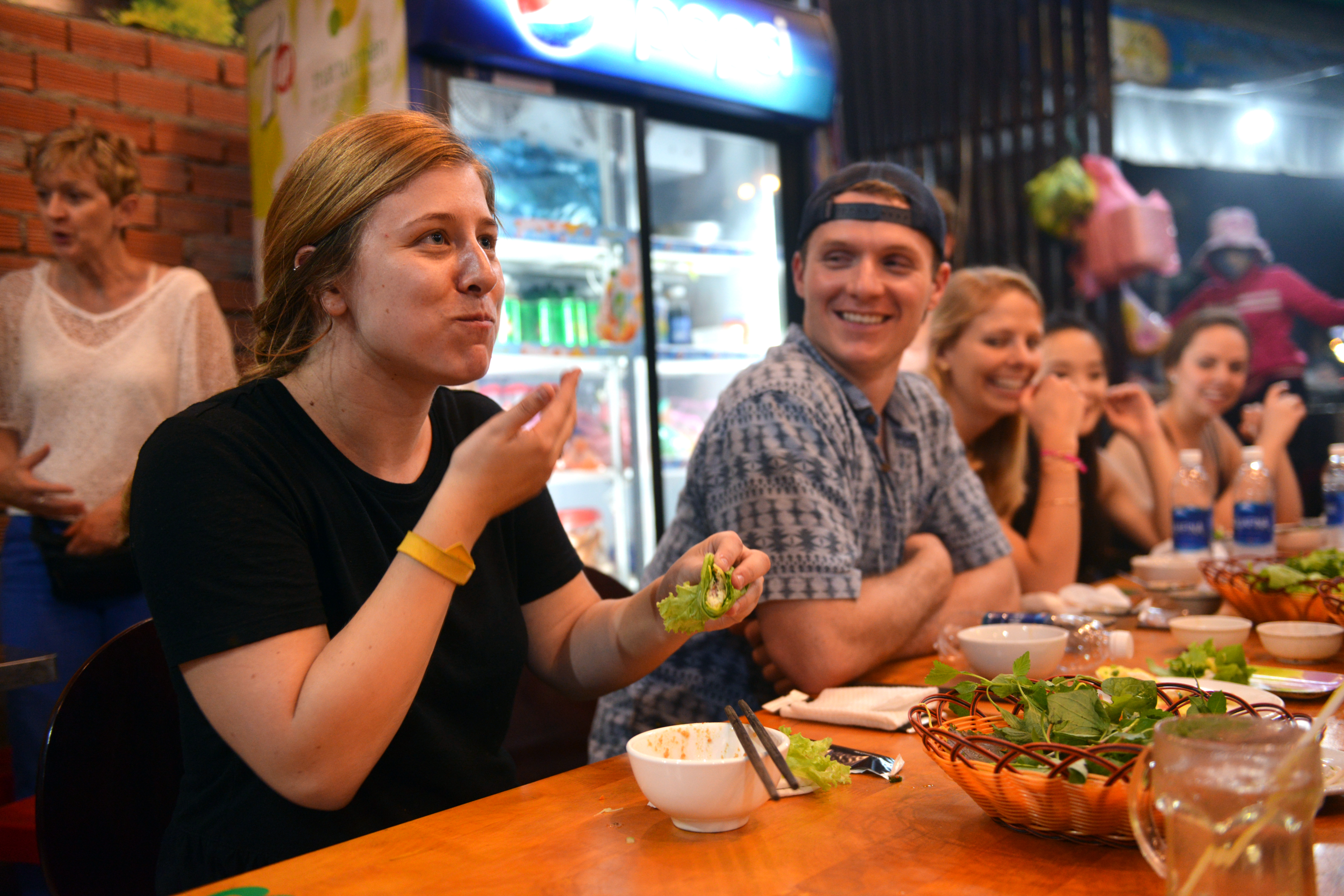 Zachary Devaney (L, 2nd) laughs when his friends try Vietnamese bánh xèo at a small restaurant in District 3, Ho Chi Minh City on December 29, 2017. Photo: Tuoi Tre