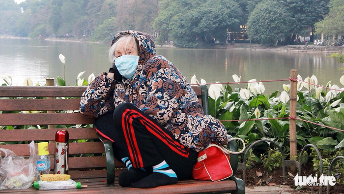An elderly woman curls up on a bench alongside Ho Guom (Sword Lake) in Hanoi on January 9, 2018. Photo: Tuoi Tre