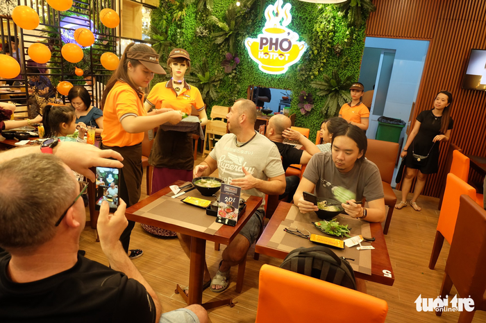 Two tourists from Hungary take photos of Co Ba the robot waitress at a restaurant in Ho Chi Minh City. Photo: Tuoi Tre