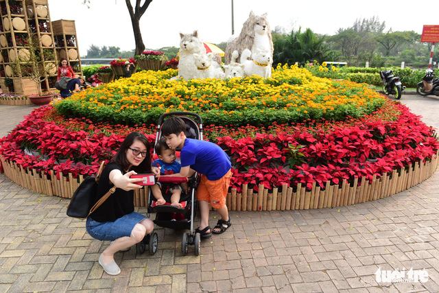 Members of a family enjoy taking photos with a colorful flower display in Phu My Hung residential area in Ho Chi Minh City on February 9, 2018. Photo: Tuoi Tre