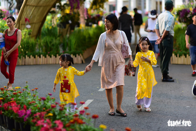 A woman, along with her two little girls, takes a stroll in the flowery Phu My Hung residential area. Photo: Tuoi Tre