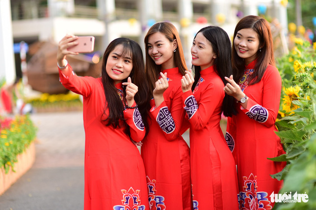 Young women wearing Vietnamese ao dai take a selfie in Phu My Hung. Photo: Tuoi Tre