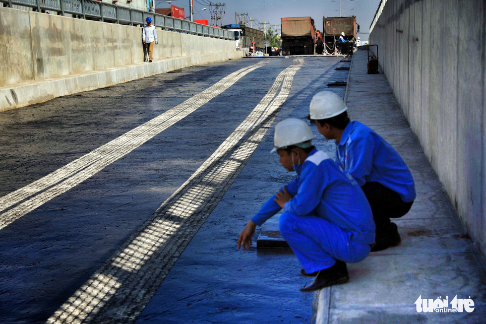 Two workers sit on the curb of the first branch of the An Suong underpass in Ho Chi Minh City. Photo: Tuoi Tre
