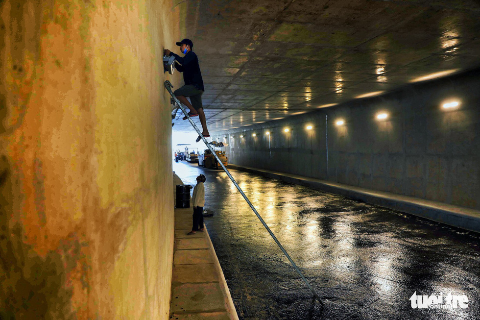 Workers install lighting systems inside the first branch of the An Suong underpass in Ho Chi Minh City. Photo: Tuoi Tre