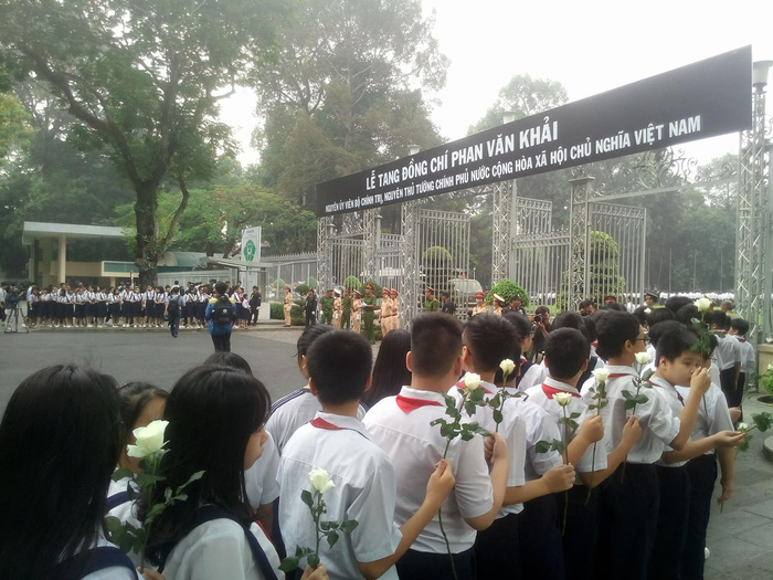 Students holding white roses line up at the entrance of the Reunification Palace.