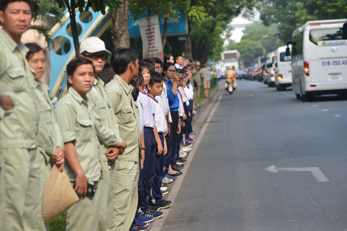 Local residents stand along Phan Thuyc Duyen Street to bid farewell to the late premier.