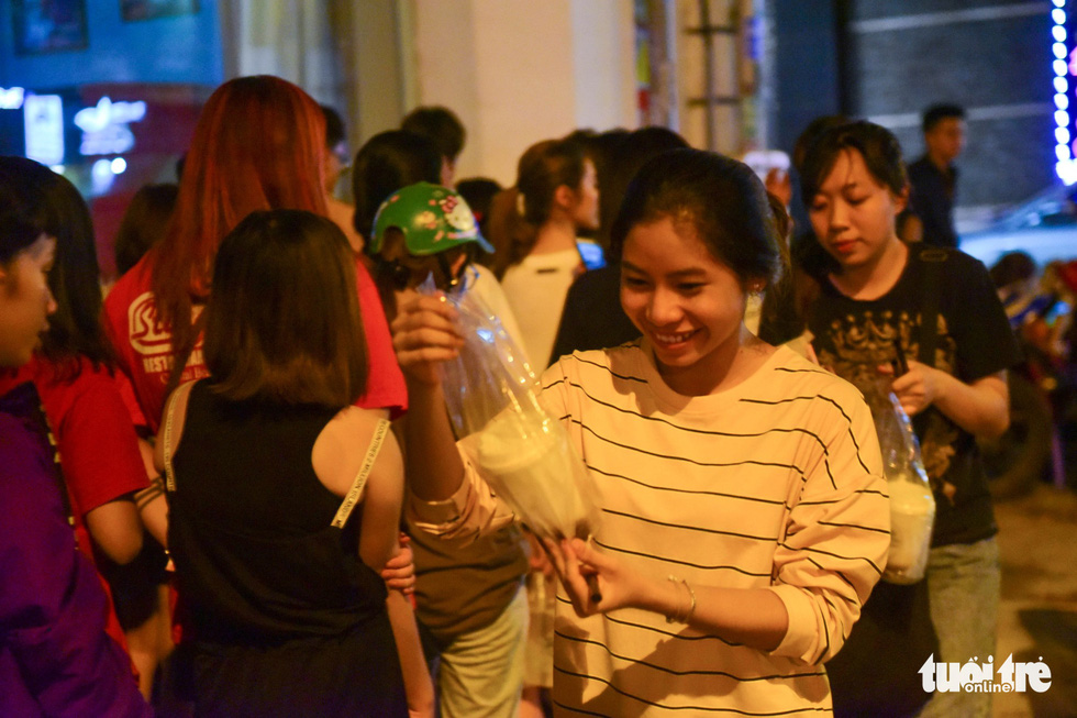 A female customer smiles brightly at the drink in her hands after hours of waiting. Photo: Tuoi Tre