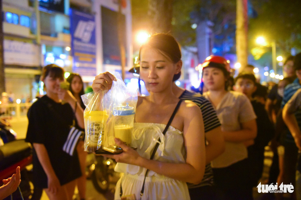 A customer hold cups of the fresh milk served with brown sugar-made tapioca balls. Photo: Tuoi Tre