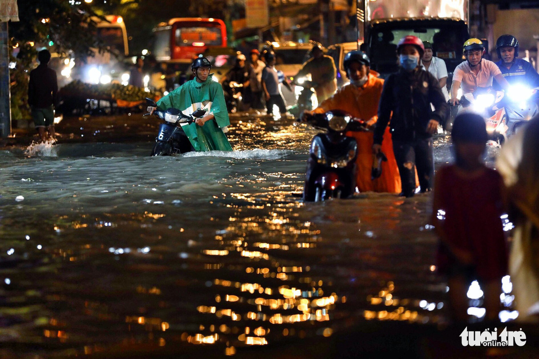 Ho Chi Minh City residents push their broken down motorbikes amid knee-deep water on the evening of May 19, 2018. Photo: Tuoi Tre
