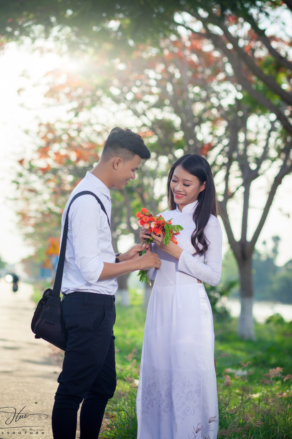 A young couple wearing school uniform pose under red flamboyant flowers in Dong Thap Province, southern Vietnam. Photo: Tuoi Tre
