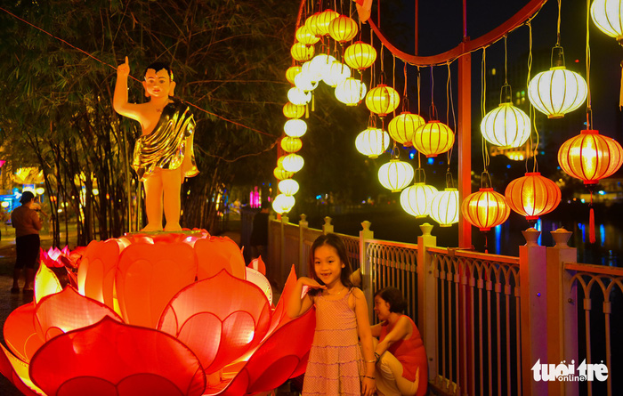 A little girl makes a pose next to the brightly-colored lanterns. Photo: Tuoi Tre
