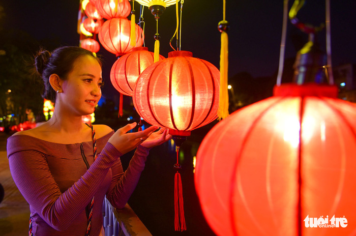 A woman watches a brightly-colored lantern. Photo: Tuoi Tre