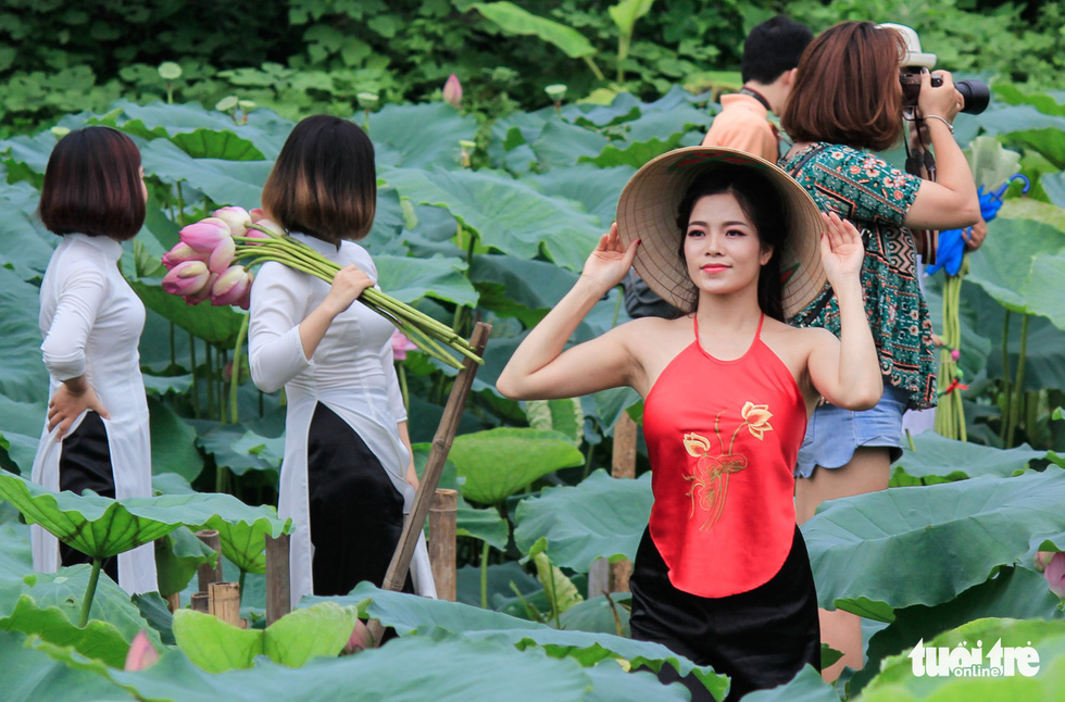 A girl in ao yem, a traditional Vietnamese bodice, poses with lotus flowers in Hanoi. Photo: Tuoi Tre