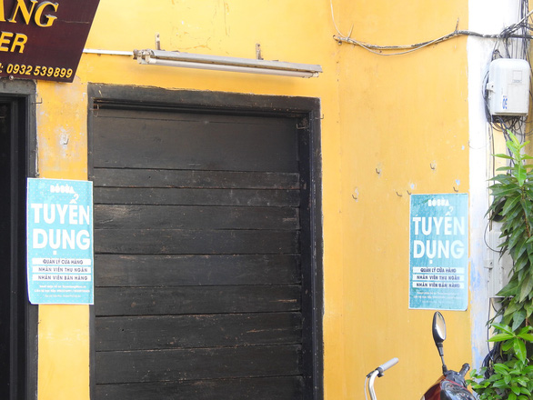 Banners belonging to private businesses  cover a wall in the ancient town. Photo: Tuoi Tre