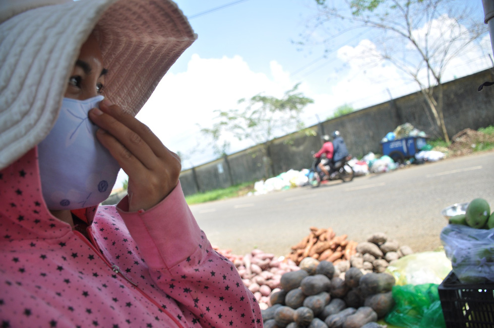 A woman covers her nose due to a putrid stench from the trash along Huynh Thuc Khang Street. Photo: Tuoi Tre