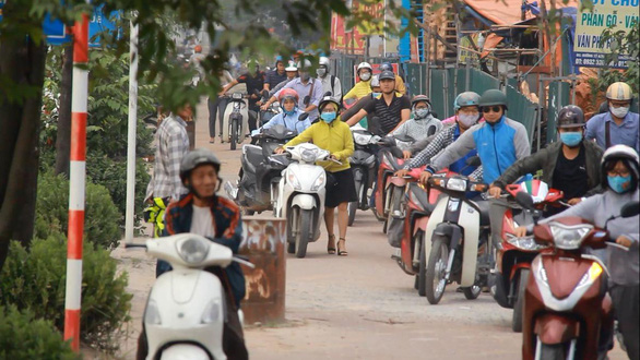 In Hanoi, commuters push motorbikes wrong way on sidewalk to avoid congestion