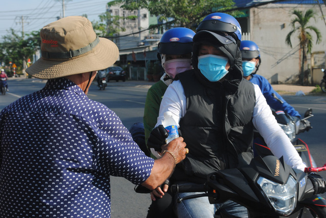 Man hands free water, tissues to people heading home for Tet reunion in Vietnam’s Mekong Delta