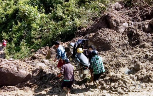 Vietnam teachers carry motorbikes across muddy paths after storm cut off access to school
