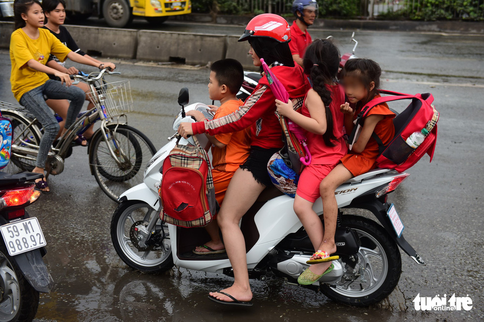 In Vietnam, parents take children to school defying compulsory helmet rule