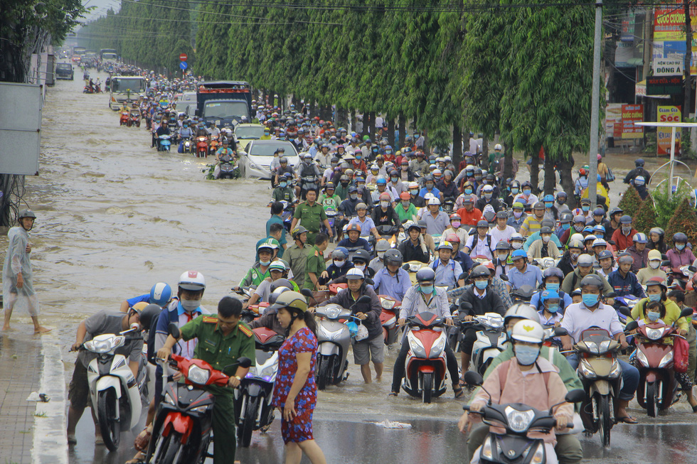 People wade through rising water on first day of week in Vietnam’s Mekong Delta city