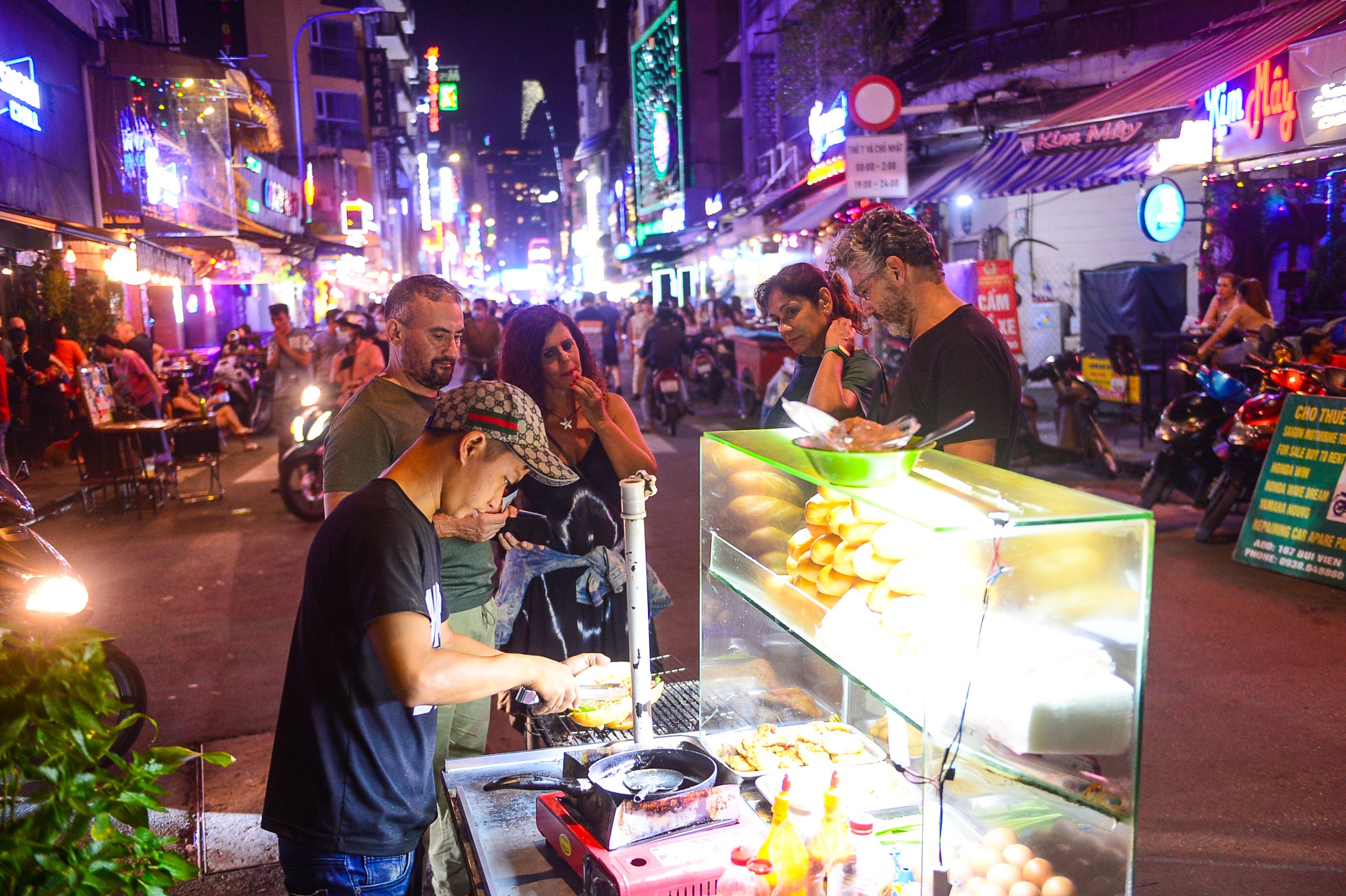 A file photo shows foreign tourists buying banh mi at a street stall in Ho Chi Minh City. Photo: Quang Dinh / Tuoi Tre