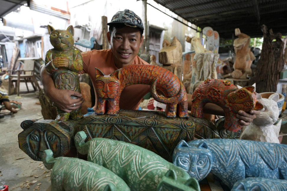 Artisan Le Ngoc Thuan, owner of a carpentry workshop in Hoi An City, shows his collection of wooden cats. Photo: B.D. / Tuoi Tre