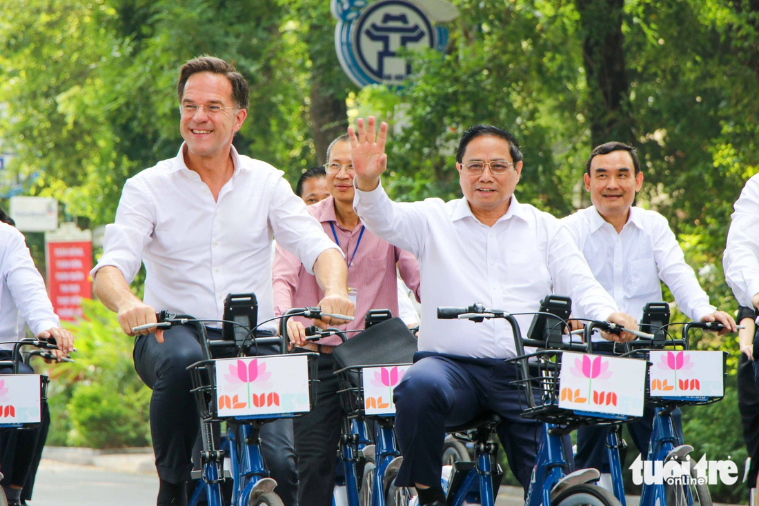 Vietnamese Prime Minister Pham Minh Chinh (waving his hand) and Dutch Prime Minister Mark Rutte (L) greet residents while cycling on Dien Bien Phu Street in Hanoi. Photo: Duy Linh / Tuoi Tre