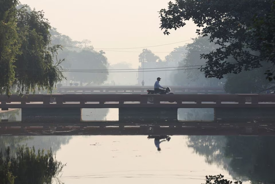 A man rides a bike on a bridge over a water body along the 'Kartavya Path' on a smoggy morning in New Delhi, India, October 27, 2023. Photo: Reuters