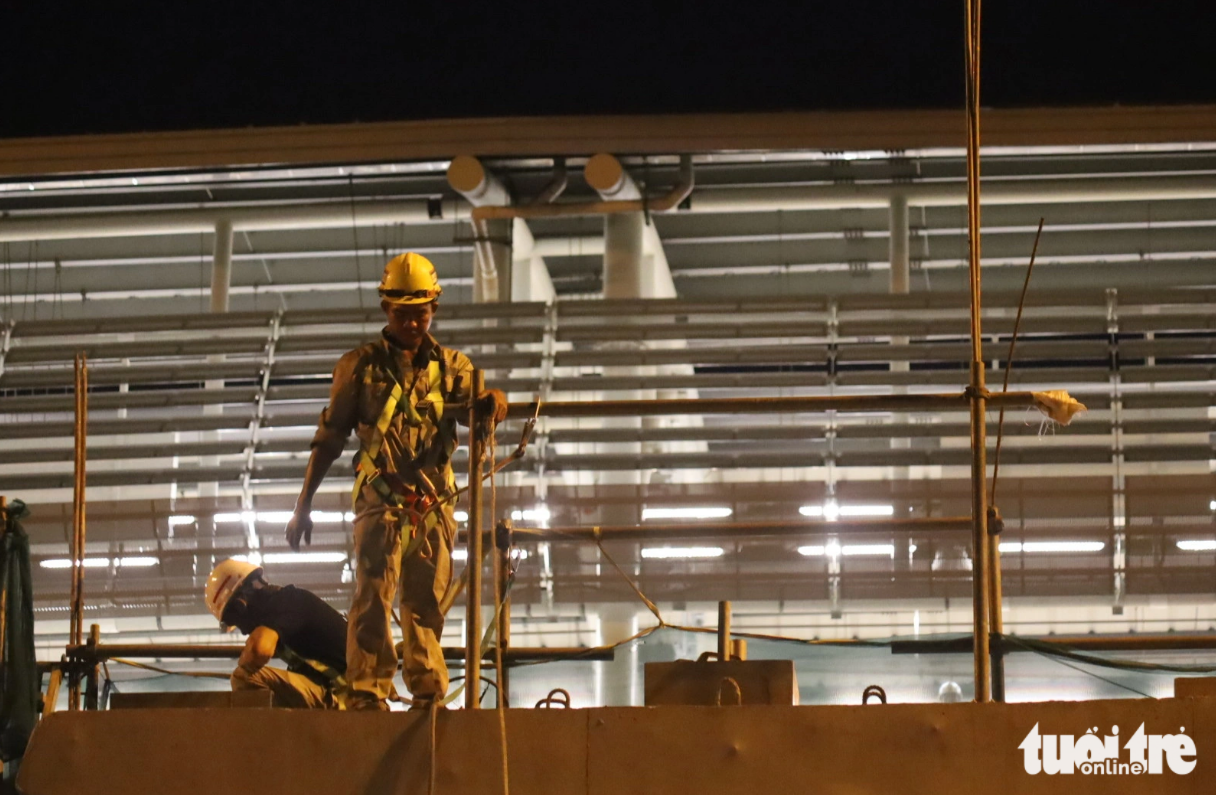 Construction workers begins beam installation on a footbridge connecting with the Saigon Hi-Tech Park station of Ho Chi Minh City’s first metro line early in the morning of November 5, 2023. Photo: Tuoi Tre