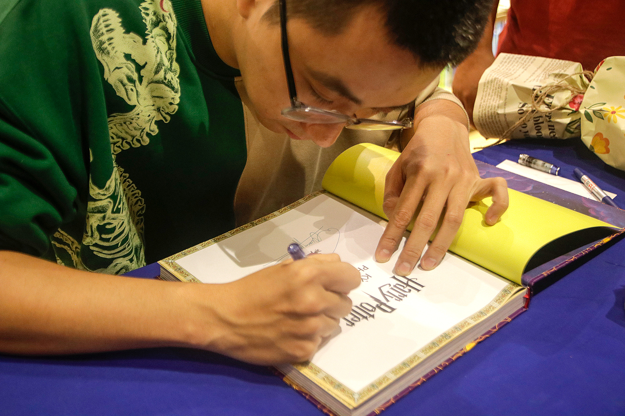 Vietnamese illustrator Pham Quang Phuc signs his autograph on ‘The Vietnamese edition of ‘The Harry Potter Wizarding Almanac’. Photo: Ho Lam / Tuoi Tre