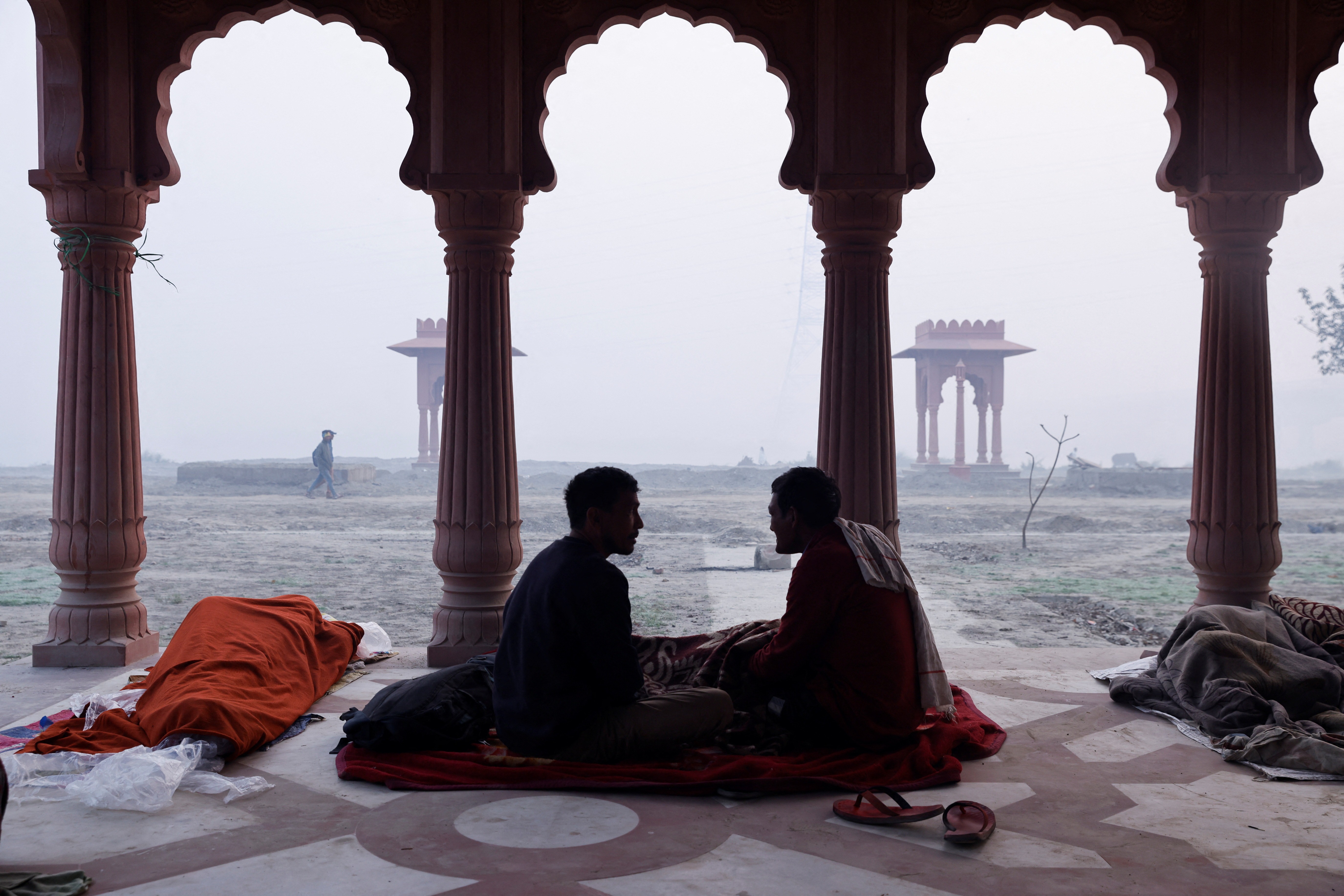 Men talk to each other on the banks of the rive Yamuna on a smoggy morning in New Delhi, India, November 13, 2023.   Photo: Reuters