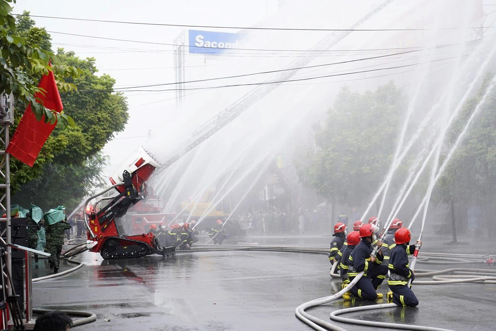 A firefighting robot and firefighters jointly put out a fire in a drill. Photo: D.Thanh / Tuoi Tre