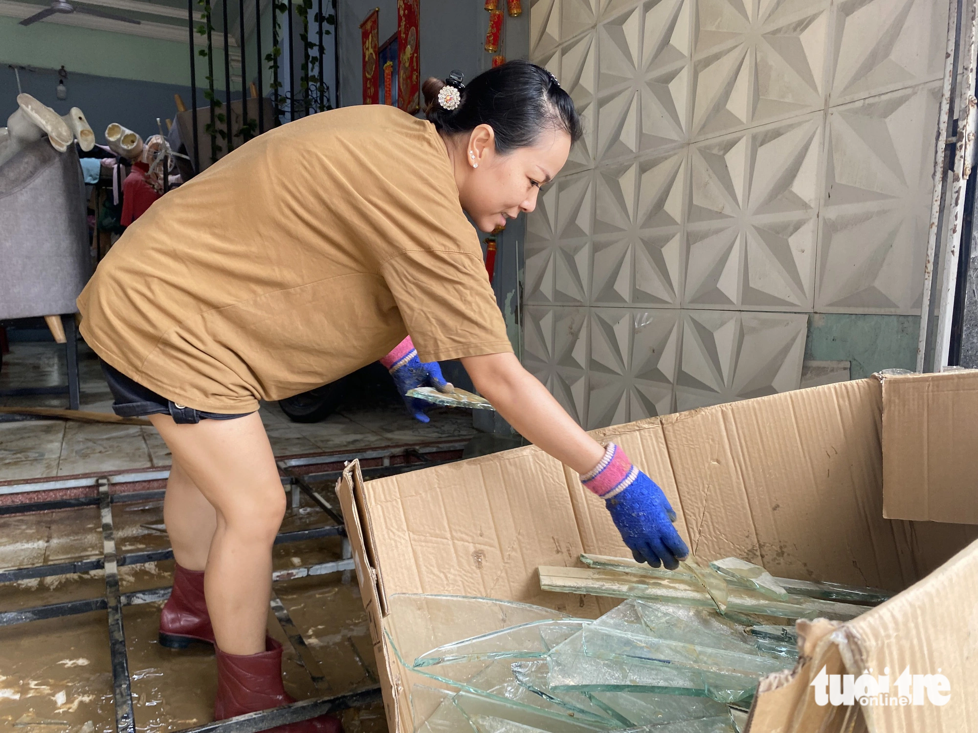 A woman throws away pieces of broken glass after the flood in Hue City, Thua Thien-Hue Province, central Vietnam, November 16, 2023. Photo: Le Trung / Tuoi Tre