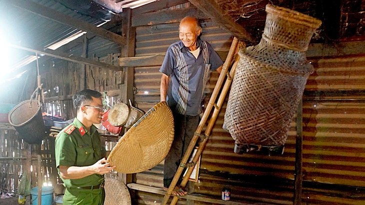 Over 100-year-old Y Pyong from the M'nong ethnic group in Ka Nur Village, Quang Khe Commune, Dak Glong District, Dak Nong Province explains his group's traditional cultural features to Bo. Photo: Duc Hung / Tuoi Tre