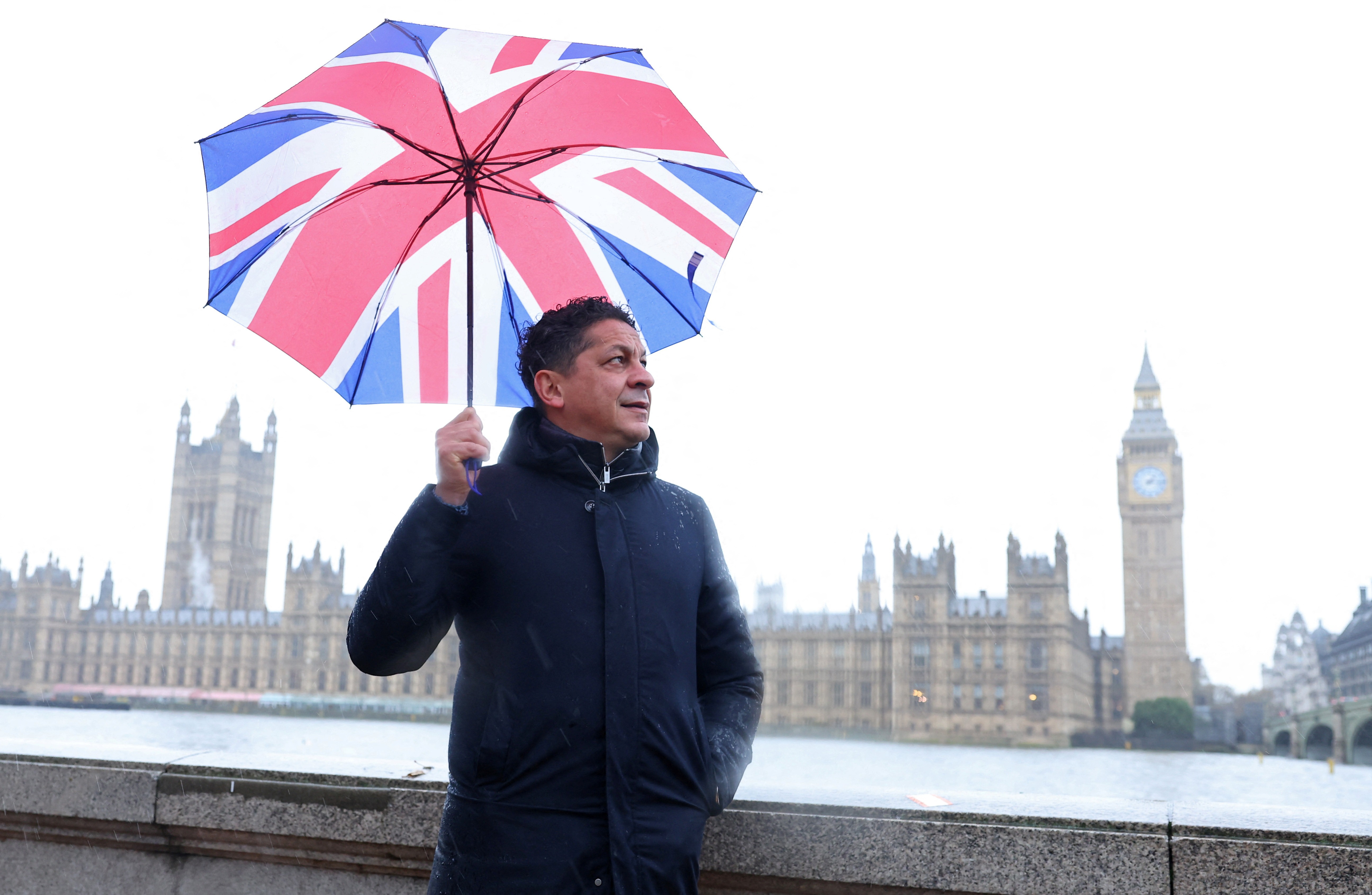 Italian chef-turned restaurant owner Francesco Mazzei shields from the rain as he poses for a portrait near the Houses of Parliament in London, Britain, November 14, 2023. Photo: Reuters