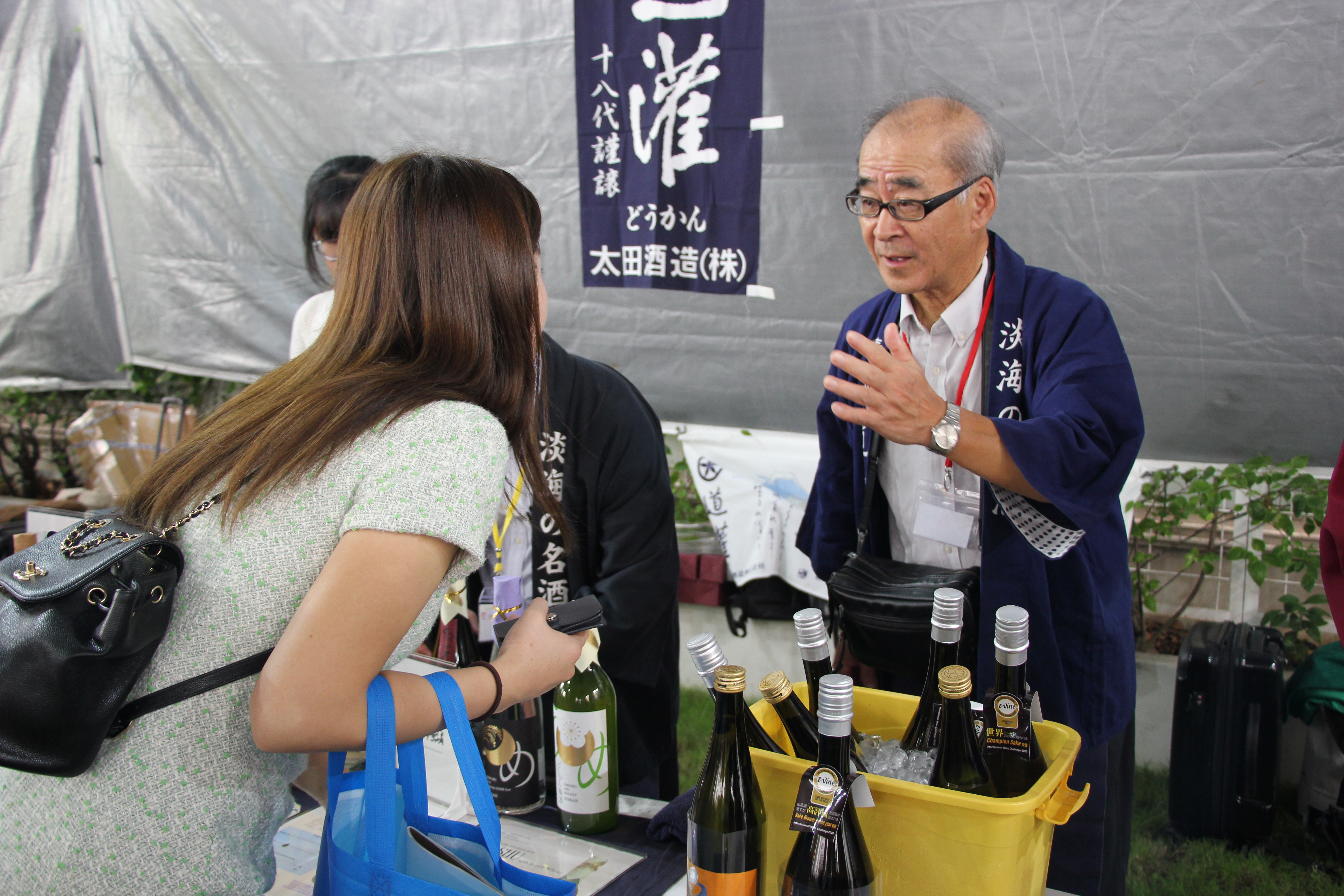 A representative of OTA Shuzou Co. Ltd., one of the 30 breweries introducing sake at the event, introduces his company's products to a visitor. Photo: Ngoc Dong / Tuoi Tre News