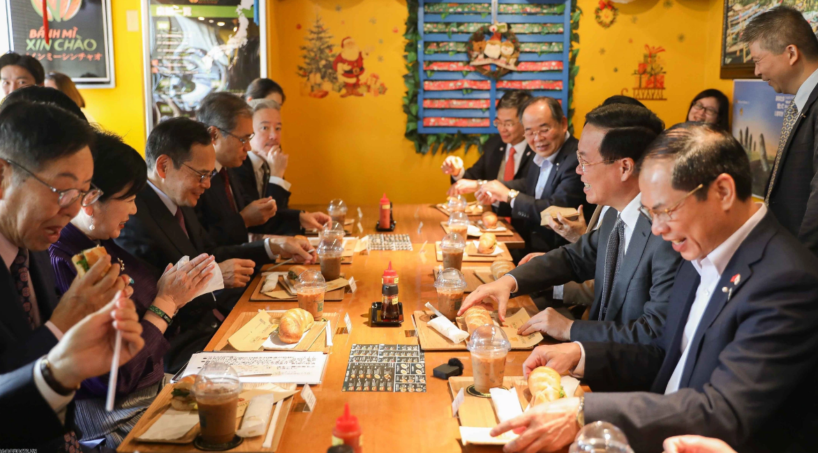 Vietnamese State President Vo Van Thuong, his spouse and other top Vietnamese and Japanese officials savor banh mi, a Vietnamese baguette filled with pate, cold cuts, herbs, cucumber, chili sauce, and pickles. Photo: Nguyen Hong / Tuoi Tre