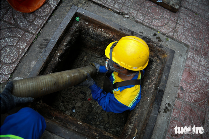 A drainage worker goes into a manhole in downtown Ho Chi Minh City to clear waste oil, fat, and grease. Photo: Phuong Quyen / Tuoi Tre