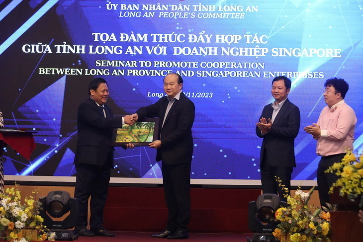 Huynh Van Son (L), vice-chairman of the administration of Long An Province, southern Vietnam presents a gift to Singaporean Consul General in Ho Chi Minh City Roy Kho for connecting Singaporean businesses with those in Long An. Photo: Son Lam / Tuoi Tre
