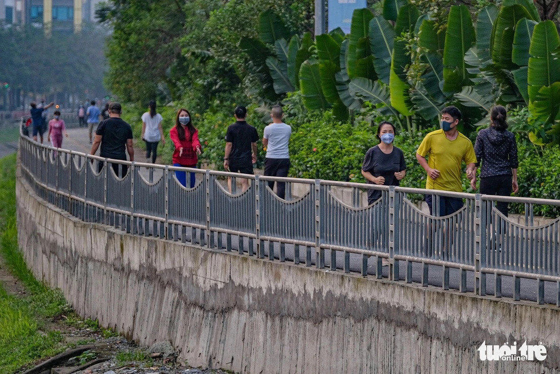 Local residents do physical exercises on a pedestrian route running along the To Lich River in Hanoi. Photo: Nam Tran / Tuoi Tre